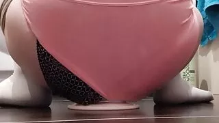 Transfrau in Strumpfhose sitzt rittlings auf einem Dildo