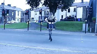 Crossdressed in Dienstmädchenuniform auf einer Straße mit vorbeifahrenden Autos