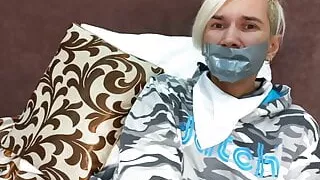 Tied up young guy with a gag.  Suffering from tickling.