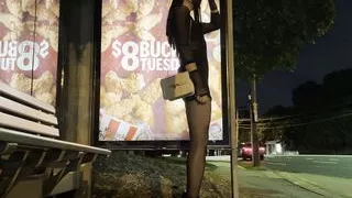 Crossdresser wartet auf den Bus in kurzem Kleid bei Nacht