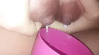 Young mom pours milk from boobs into a cup