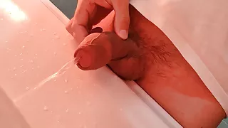 Young guy pissing in the washbasin