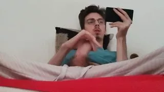 Twink jerks off his big cock and ejaculates while watching a porno