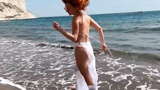 Sexy red-haired girl enjoys a walk by the sea